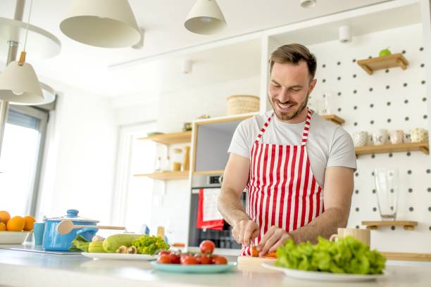 istock Man wearing a white apron with red lines and cooking something in the kitchen 1437451298