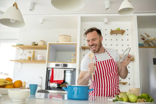 istock Man wearing a white apron with red lines and cooking something in the kitchen 1437451303