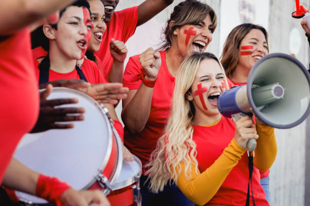 fãs de futebol multirracial comemorando vitória da equipe vermelha em jogo do campeonato no estádio - torcedores de futebol se divertindo na multidão - red white american football stadium soccer stadium - fotografias e filmes do acervo