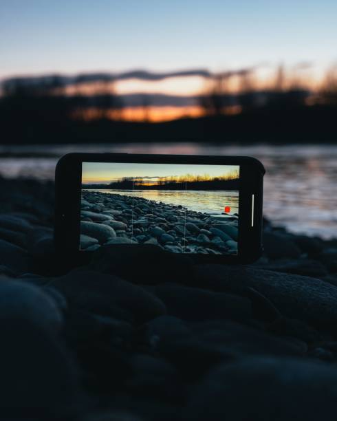 A smartphone on the coast recording the sunset over the river with tree silhouettes