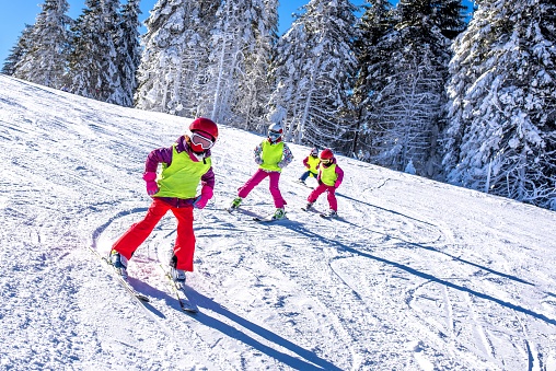 A group of kids learning how to ski on a slope in mountains