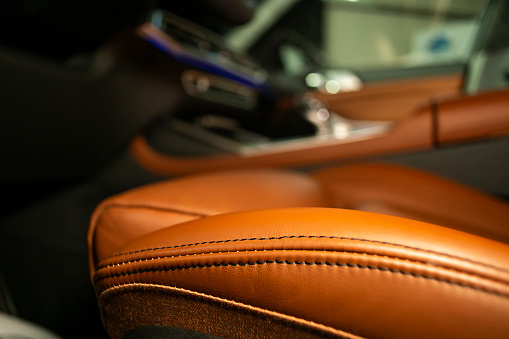 Soft focus close up of an orange leather driver's seat inside a luxury car