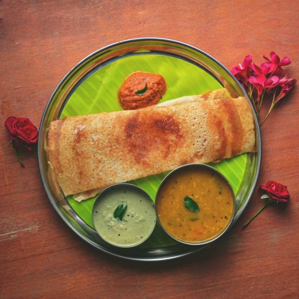 Top view of dosa served with aloo rasedar and sauce on a tray