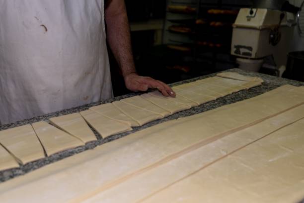 istock Baker cutting the dough into triangles for making croissants in a pastry shop 1437454874
