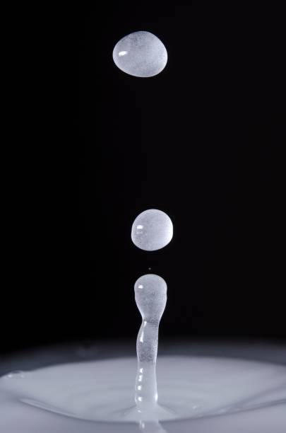 istock Vertical closeup of waterdrops bouncing above a white liquid against a dark background 1437455176