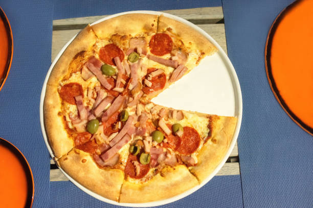 Appetizing pizza on a table in a cafe. Pizza with sausage and olives.