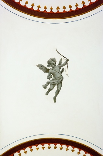 A vertical shot of a grey cupid on a white ceiling
