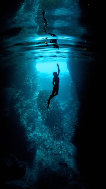 istock Underwater vertical shot of a diver reaching toward the surface with one hand 1437457387