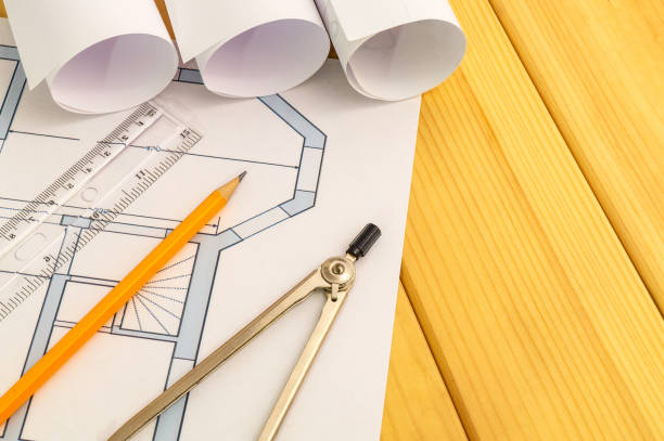 istock Rolled house diagrams and accessories for drawing lying on construction drawing and wooden boards 1437458632