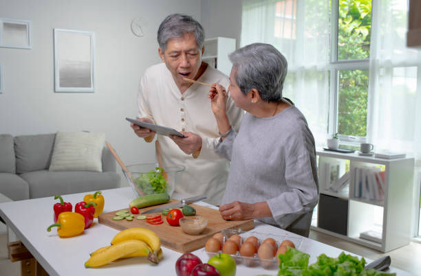 istock Happy Asian senior couple using tablet and testing food while cooking in the kitchen. 1437459993