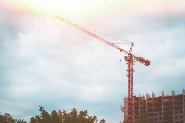 grue de construction dans les rayons de soleil éclatant. maison en construction et grue. - fill frame flash photos et images de collection