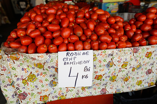 Shallow depth of field (selective focus) details with tomatoes on a stand in Obor market in Bucharest, Romania.