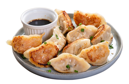 Taiwanese and Japanese Pan-fried gyoza dumpling jiaozi food in a plate isolated on white background.