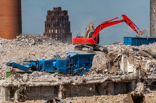 The demolition of a building with heavy equipment in the midst of construction debris