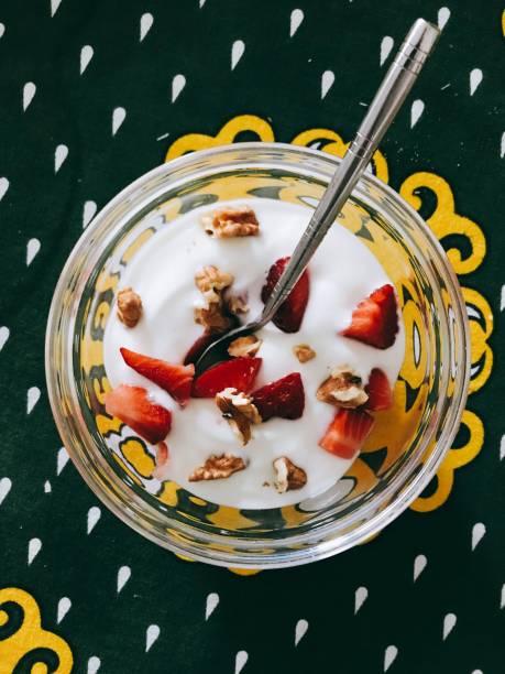 High angle shot of yoghurt with nuts and strawberries in a bowl on the table