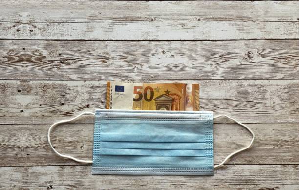 istock Protective mask and euro on wooden table- COVID-19 1437480469
