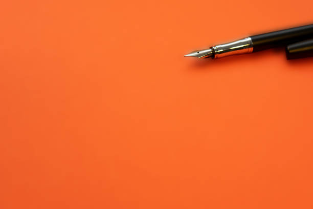 A closeup of a ballpoint pen on orange background with copy space