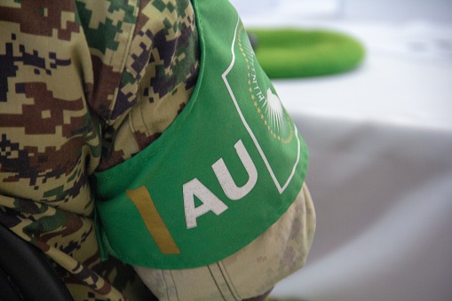 A soldier from the African Union Mission in Somalia (AMISOM), wears a green armband over his camouflage uniform reading AU (African Union).