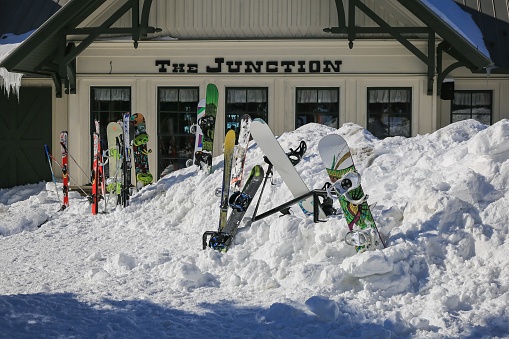 Snowshoe, WV, United States – February 27, 2015: Snowboards in a  mound of snow in front of a Snowshoe Resort mountain top restaurant called The Junction..