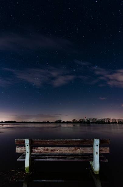 istock Vertical shot of a bench in the water at night 1437481236