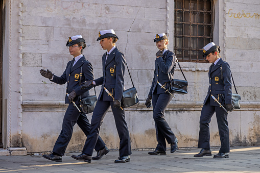 Venice, Italy - October 6th 2022: Four formally dressed pretty young female naval officers from the Italian navy walking in the afternoon sun in the old and famous Italian city Venice