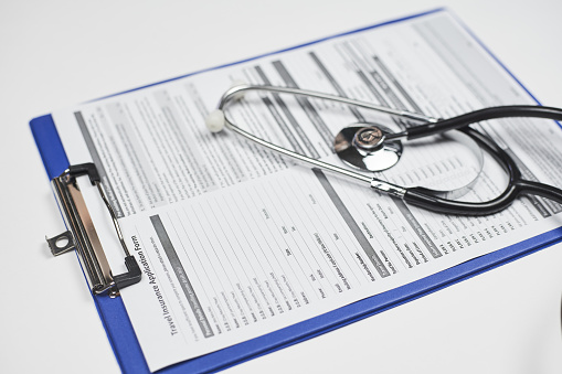 A high angle closeup shot of a stethoscope on a travel insurance application document