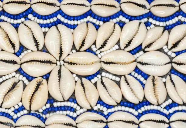 Photo of Closeup of a stringed white and blue strings and cowrie shells forming a pattern