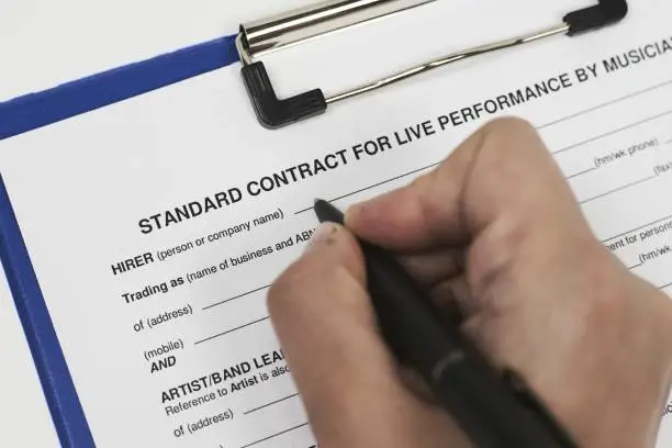 Photo of Closeup of a person signing a Standard contract for live performance by musicians