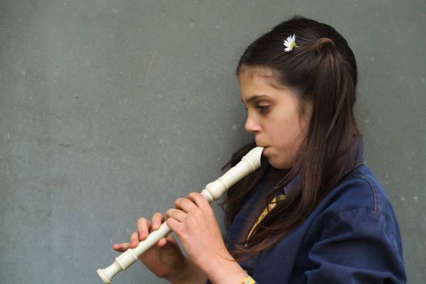 niña tocando una grabadora aislada sobre un fondo gris - recorder fotografías e imágenes de stock