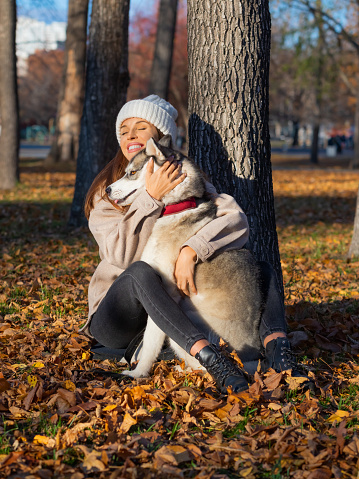 A young woman embracing her dog, a husky. Concept of psychological recovery through communication with animals. Love, care and understanding. Vertical photo.