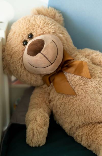istock Vertical shot of a smiling brown teddy bear with a bow 1437485588