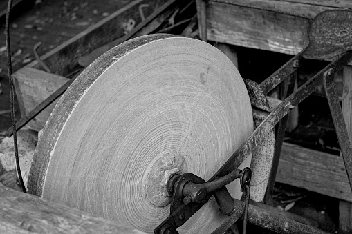 A closeup grayscale shot of antique grindstone for sharpening knives