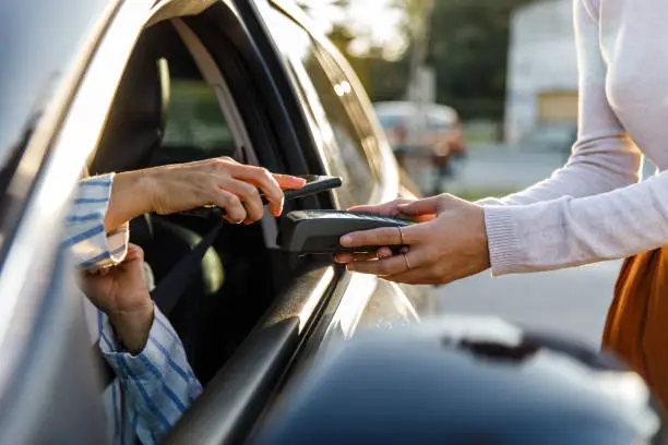 Photo of Customer paying for her order with smart phone, at the curbside pickup