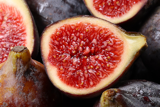 Several ripe prickly pear fruits lie in a ceramic bowl. The bowl stands on a base made of rustic wood. There is space for text.