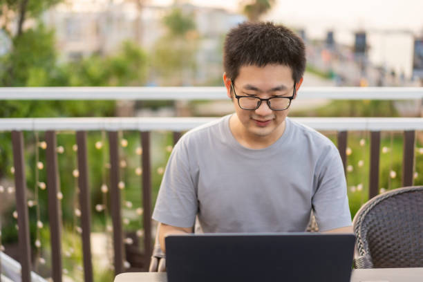istock Asian male freelancer using a laptop in an open-air cafe by the river 1437495835