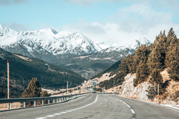 istock Long road surrounded by high mountains with tops covered in snow 1437496116