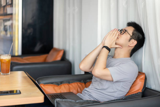 istock Asian male freelancer getting tired while working in cafe 1437496335