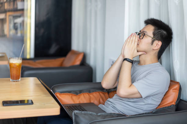 istock Asian male freelancer getting tired while working in cafe 1437496366
