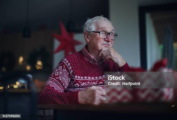 Unhappy Senior Man Sitting Alone And Waiting For Family During Christmas Eveconcept Of Solitude Senior And Mental Health Stock Photo - Download Image Now