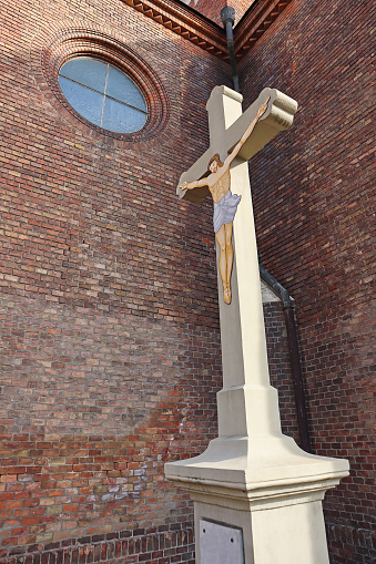 Jesus Christ figure on the cross in front of the brick wall of the church