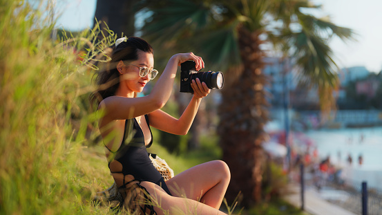 A young female tourist is taking photos and videos by the sea.
