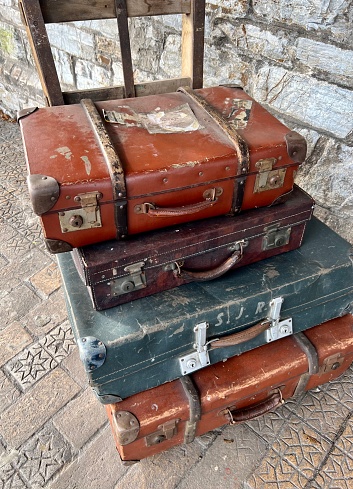 Close up stack of four old vintage antique grunge travel luggage brown leather suitcase with vintage sign. Travel luggage concept. Retro style filtered photo