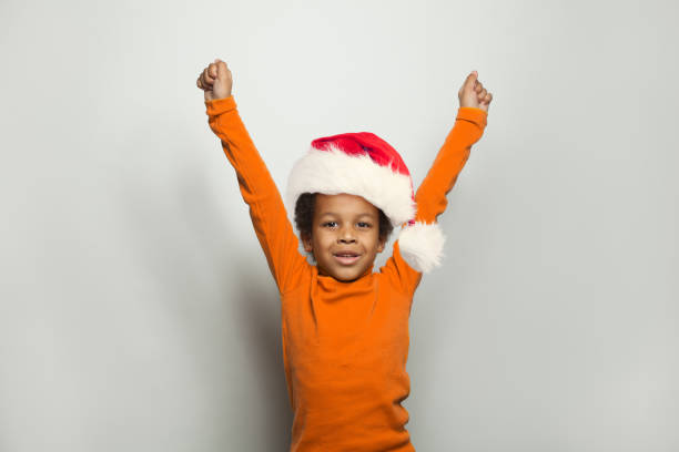 Little black kid boy in Santa hat having fun on white background