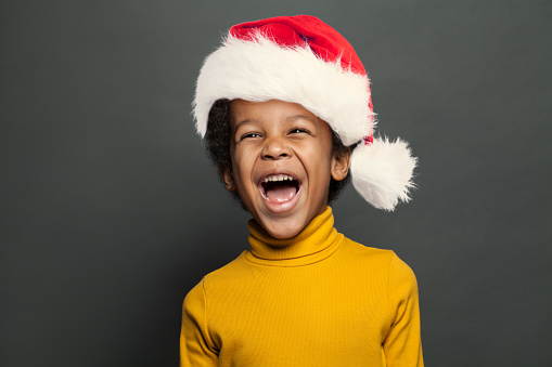 Laughing kid in Santa hat on gray background