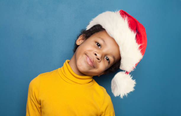 istock Curious black child boy in Santa hat smiling on blue background 1437503672