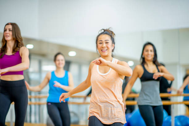 Women's Aerobics Class A small group of mature woman stand spread apart in a fitness studio as they participate in an Aerobics class together.  They are each dressed comfortably in athletic wear and are smiling as they enjoy themselves. aerobics stock pictures, royalty-free photos & images