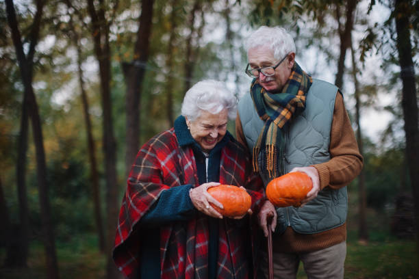 istock Senior couple with pumpkins in autumn forest. 1437506591