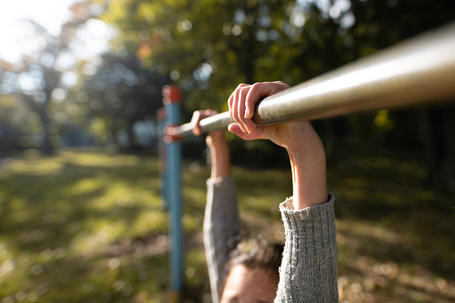 Child's hand playing horizontal bar in the park