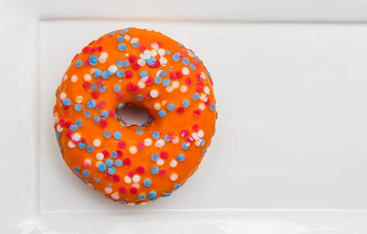 Orange donut with sprinkles in the colors of the dutch flag for celebration of Koningsdag holiday