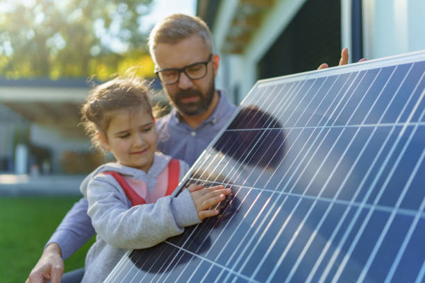 Father showing his little daughter solar photovoltaics panels, explaining how it works. Alternative energy, saving resources and sustainable lifestyle concept. stock photo